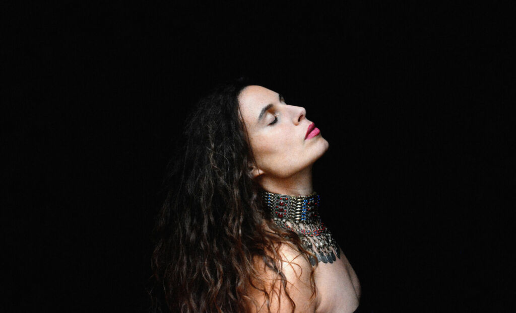 L'artiste sur fond noir, de profil et tête basculée vers l'arrière