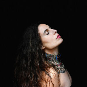 L'artiste sur fond noir, de profil et tête basculée vers l'arrière